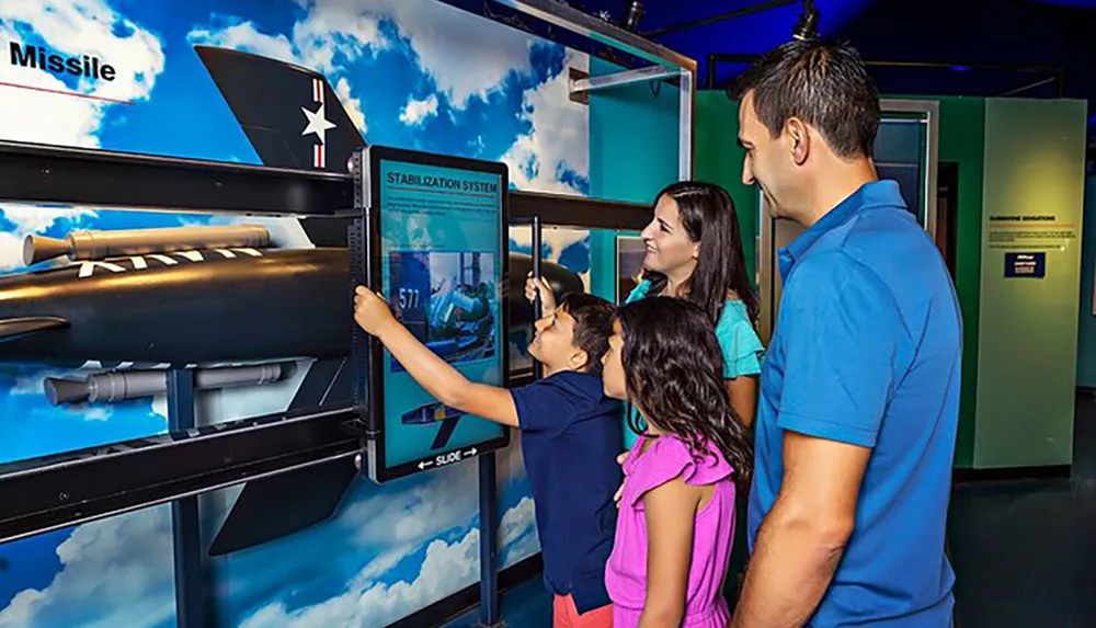 A family is engaging with an interactive exhibit about a missile stabilization system at a museum
