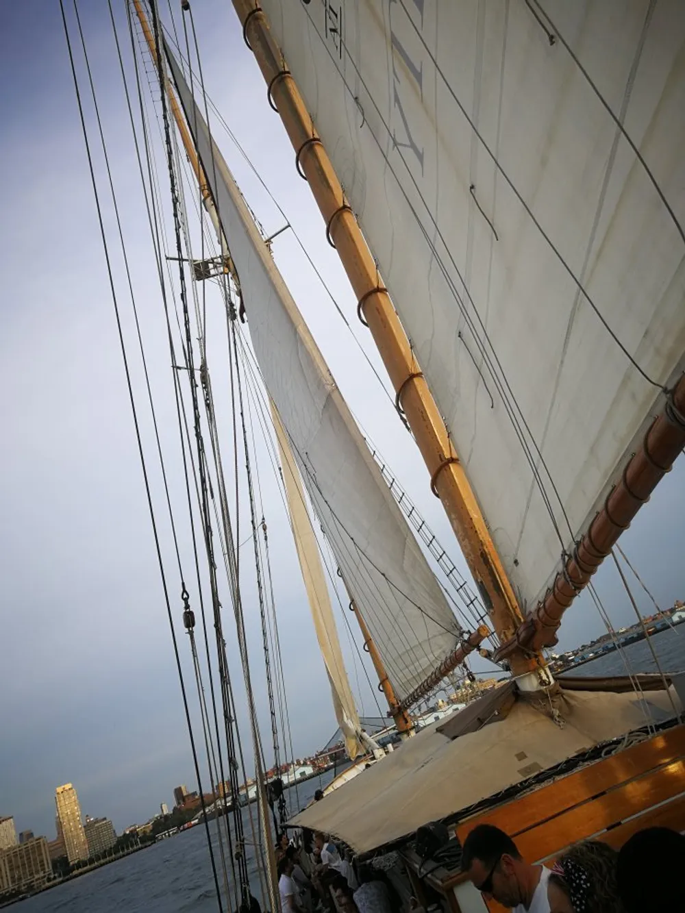The image shows a group of people on a sailing ship with its billowing sails hoisted up the masts