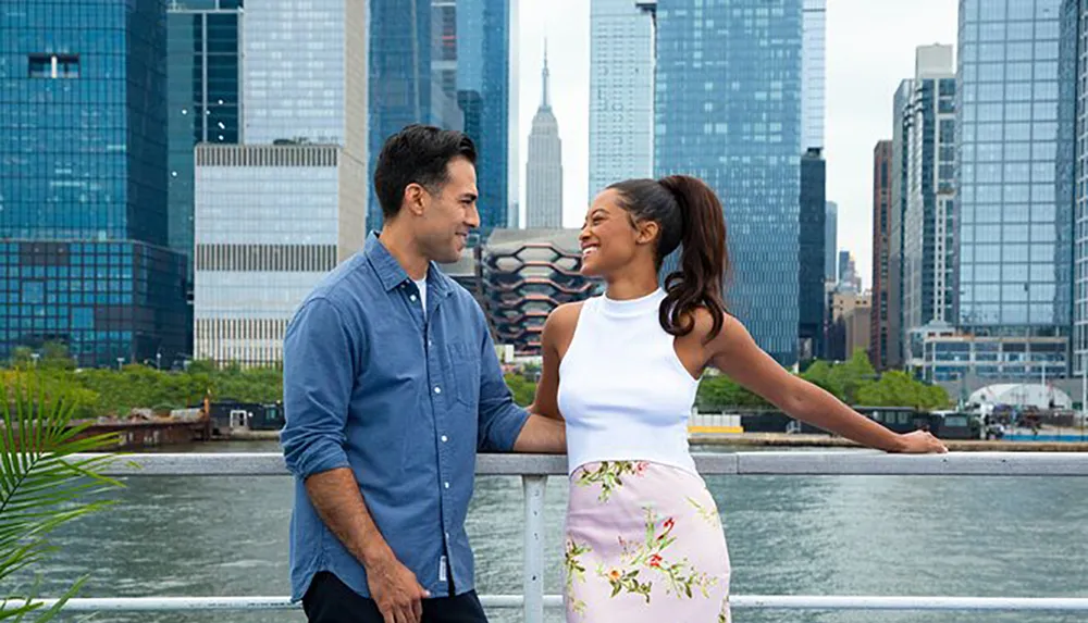 A man and a woman are smiling at each other with a city skyline in the background