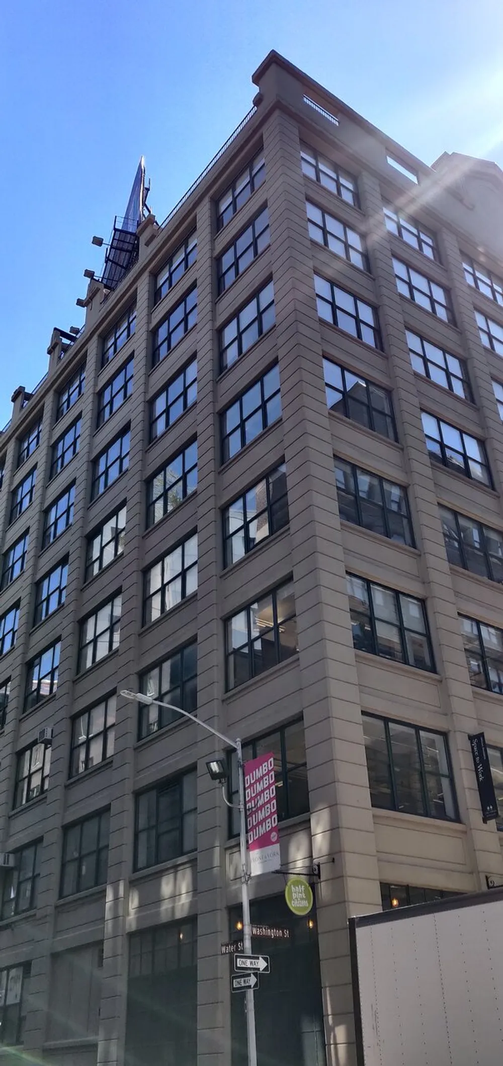 The image shows a multi-story building with a large banner reading DUMBO on its facade located at the corner of Water St and Washington St under a clear blue sky