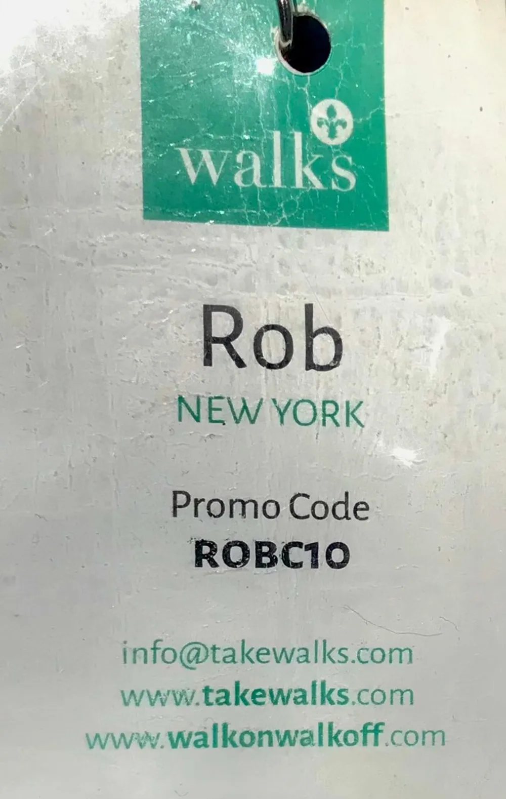 The image shows a worn name tag or badge displaying the name Rob a location New York a promotional code and two website addresses related to walking tours