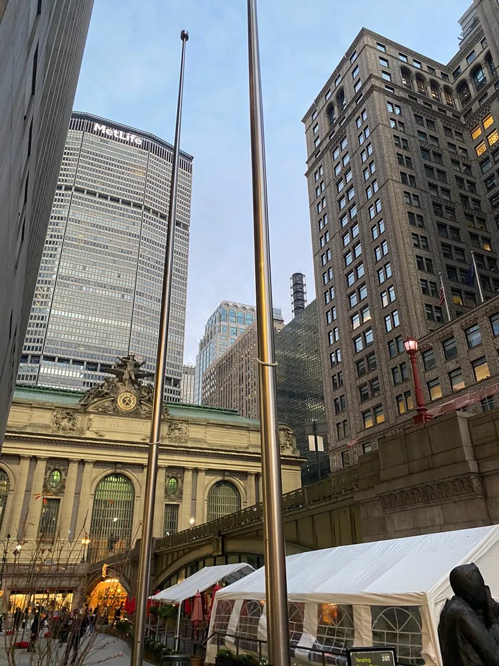 The image captures a cityscape with a mix of architectural styles showcasing the facade of a classic building in the foreground modern skyscrapers in the background and a flagpole without a flag to the left suggesting an urban setting likely in a downtown area