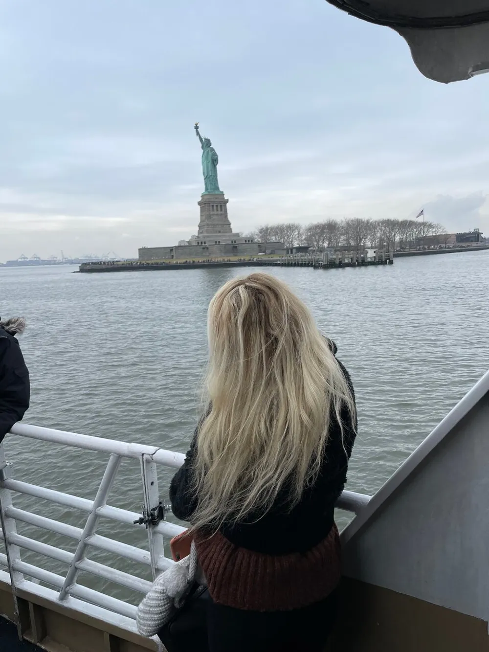A person is gazing at the Statue of Liberty from a boat