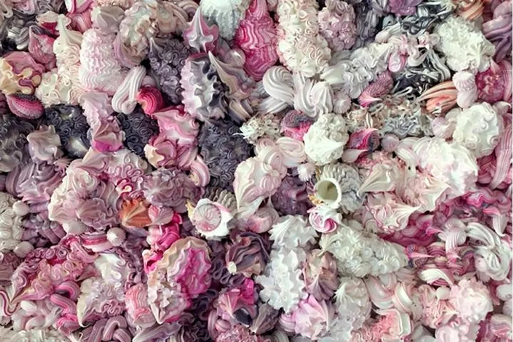 The image shows an assortment of pink and white meringues in various shapes and textures creating a visually appealing pattern of confectionery