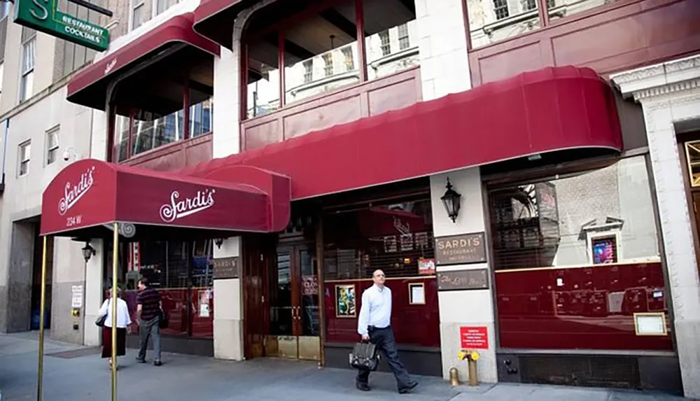 A man walks by the iconic entrance of Sardis restaurant a well-known establishment in the theater district with its red awnings and elegant signage
