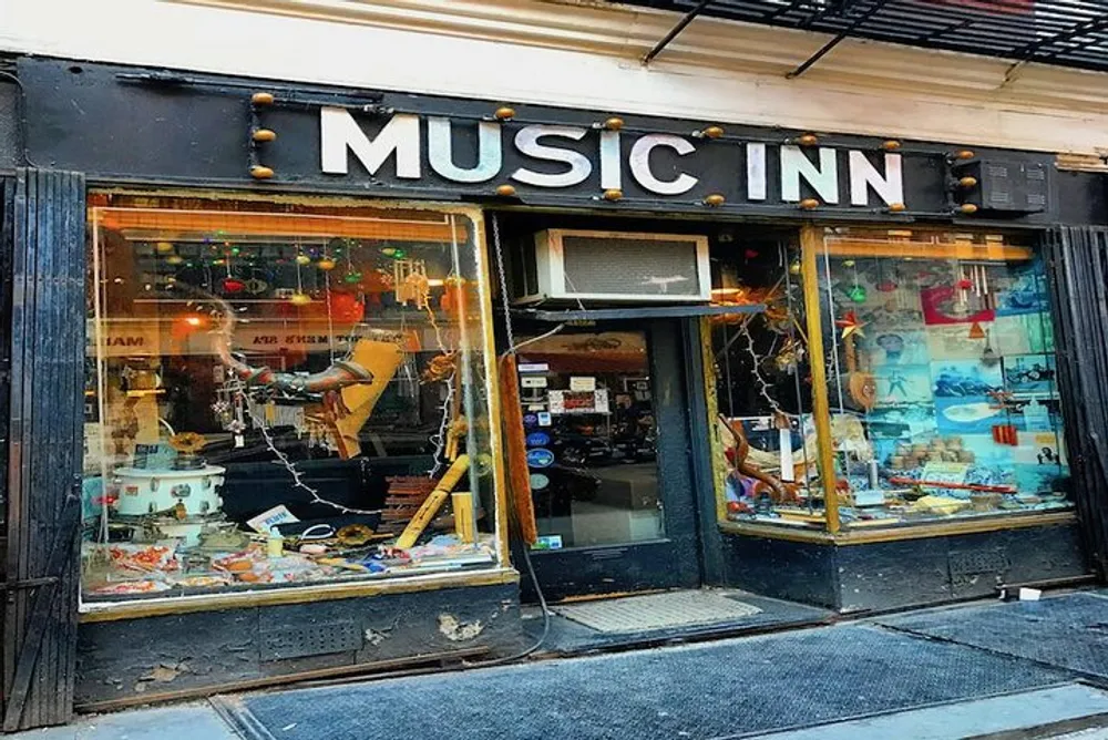 The image shows the exterior of a music store named MUSIC INN featuring a window display filled with various musical instruments and equipment