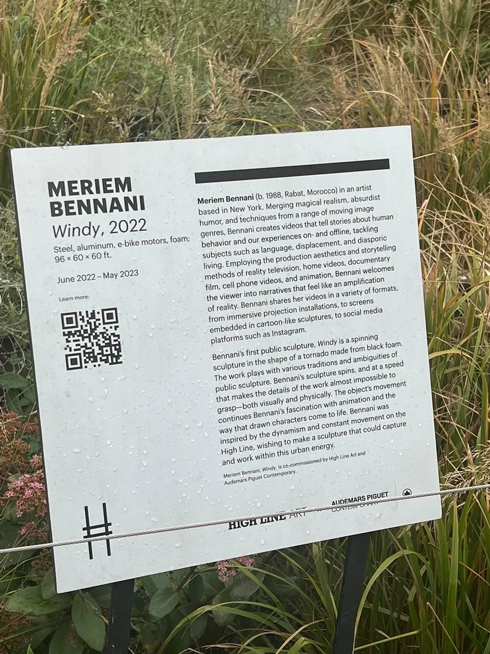 The image shows an information panel about an artwork titled Windy 2022 by Meriem Bennani mentioning the materials used and providing context about the artist and the work with a QR code and logos of the sponsoring organizations at the bottom