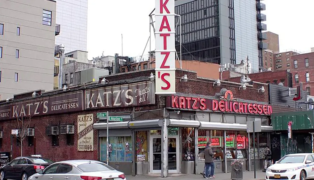 The image shows the iconic Katzs Delicatessen a famous New York eatery with its distinctive red neon sign and an advertisement of its establishment in 1888