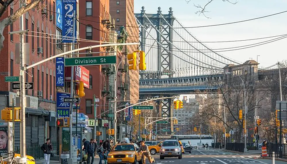 The image depicts an urban street scene with pedestrians and vehicles numerous signs in Chinese characters and the distinctive structure of the Manhattan Bridge in the background