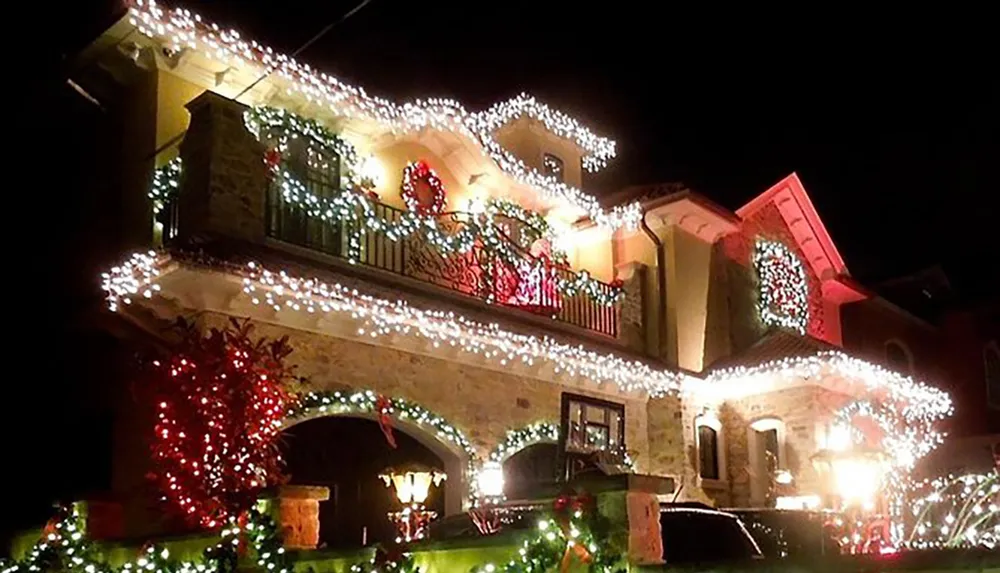 A house is festively adorned with numerous Christmas lights and decorations creating a warm holiday atmosphere at night