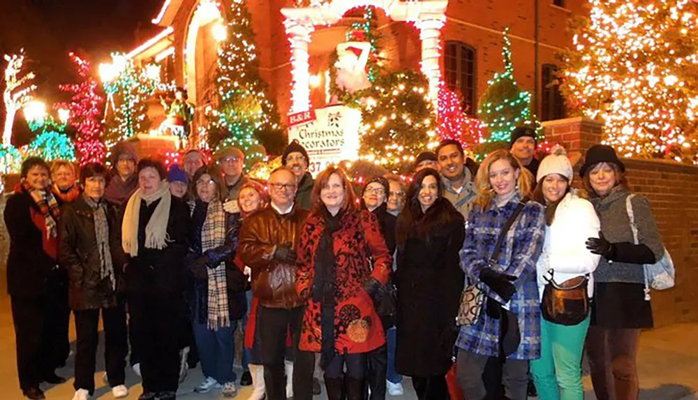 A group of people are posing for a photo in front of a brightly decorated building with Christmas lights at night