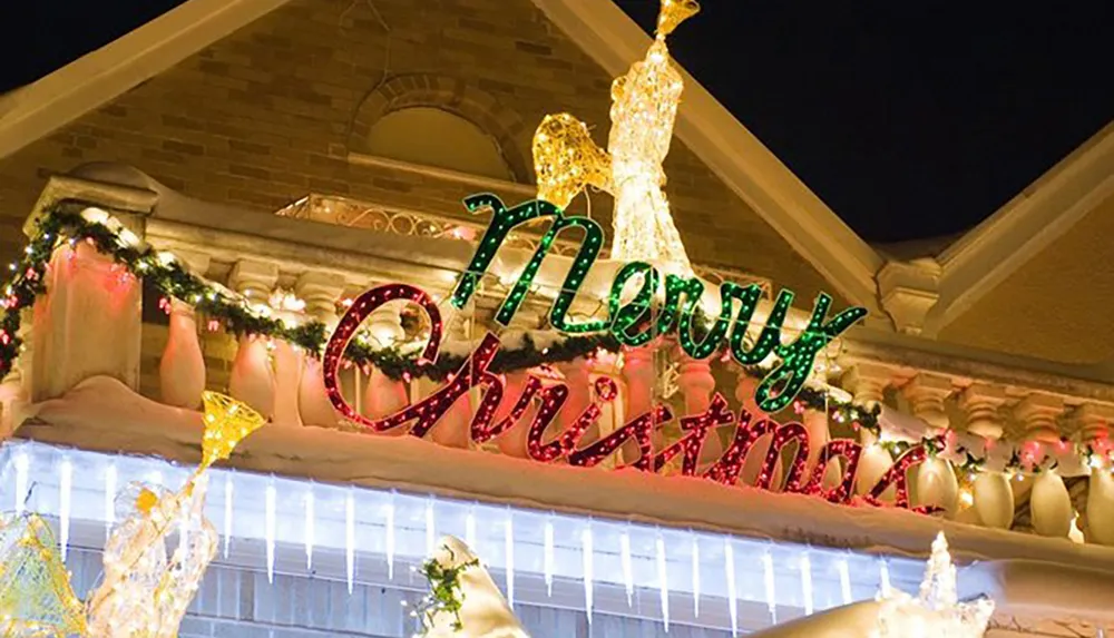 The image shows a festive rooftop Christmas decoration with illuminated text reading Merry Christmas and various light sculptures including reindeer adding to the holiday spirit
