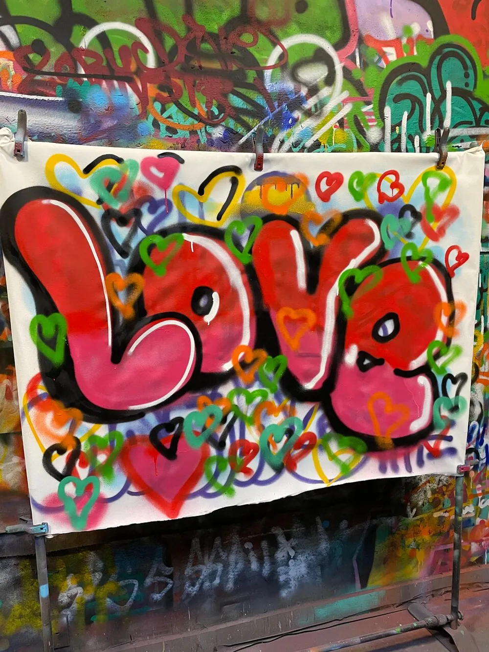 The image features a vibrant graffiti-style artwork with the word Love in bold letters surrounded by multicolored hearts displayed against a backdrop of various other graffiti