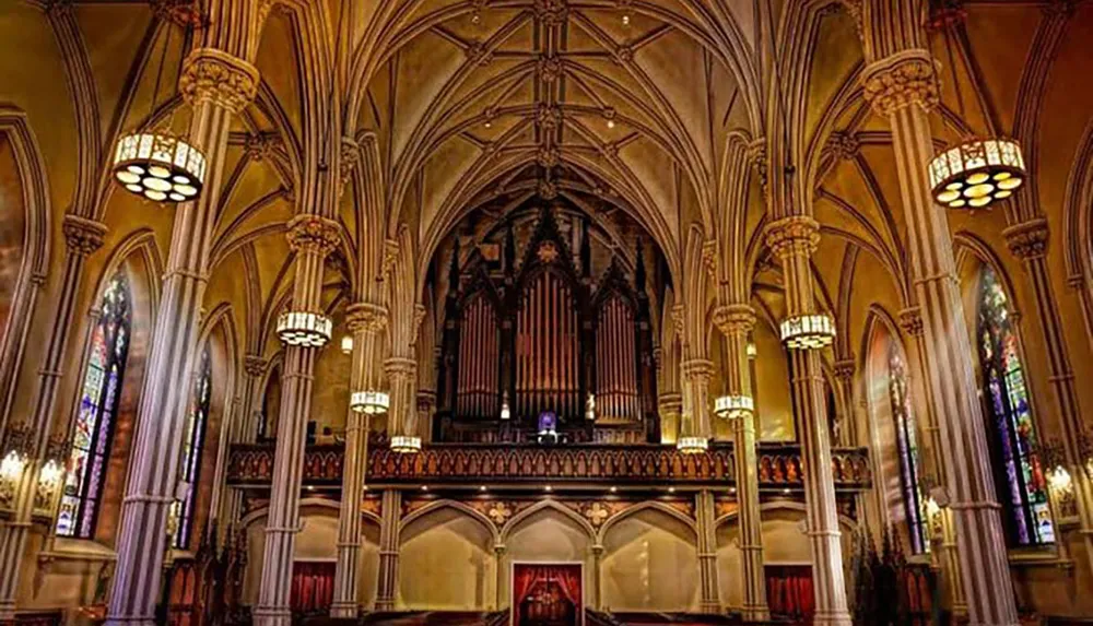 The image depicts the ornate interior of a Gothic cathedral with soaring arches stained glass windows and a large pipe organ