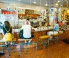 This image shows a group of customers seated on unique swing-like bar stools at a coffee shop counter while a barista works in the background