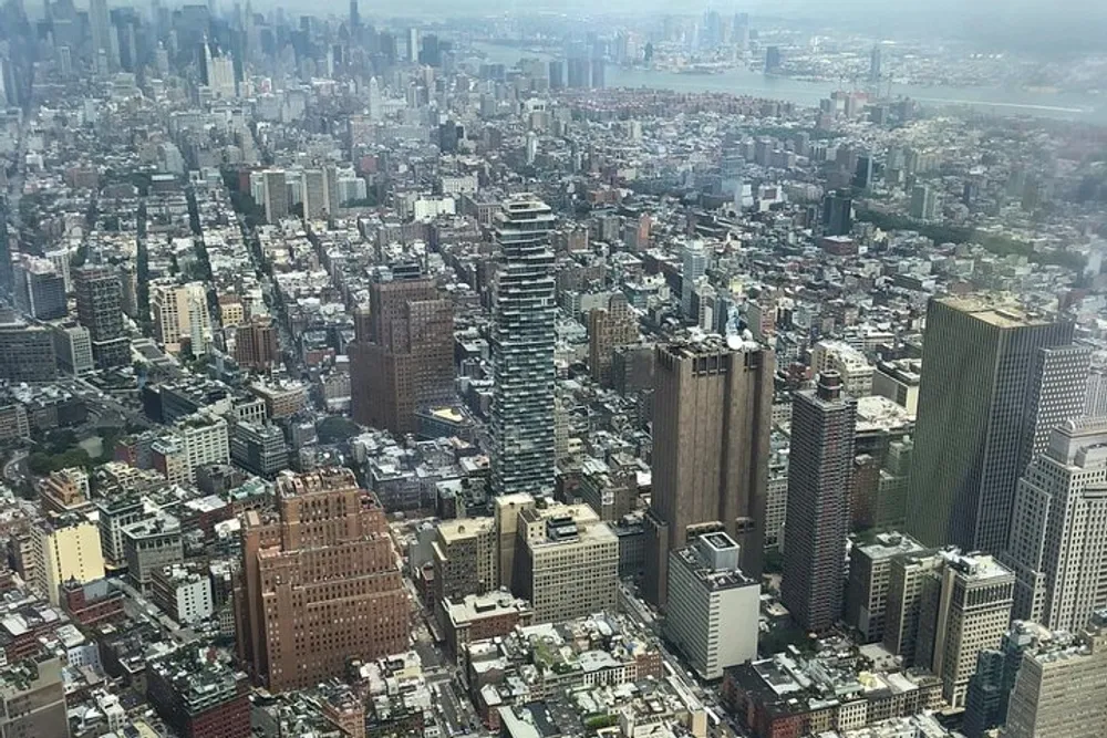 A high-angle view of a densely packed urban area with numerous buildings of varying heights and architectural designs under a hazy sky