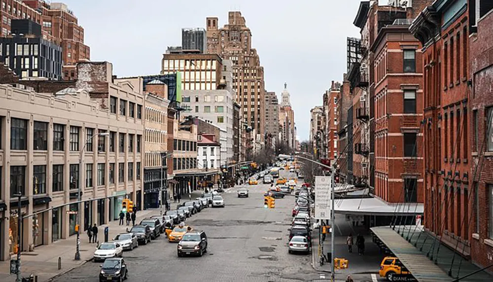 This image captures a bustling urban street flanked by a mix of modern and traditional buildings with numerous cars and iconic yellow taxis indicative of a busy city likely New York under an overcast sky