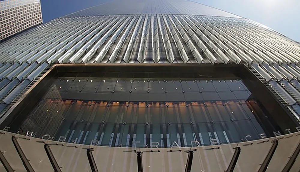 The image is a low-angle view of the exterior of the World Trade Center highlighting its modern architectural design and the vastness of its structure