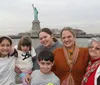 A group of people are posing for a photograph in front of the Statue of Liberty