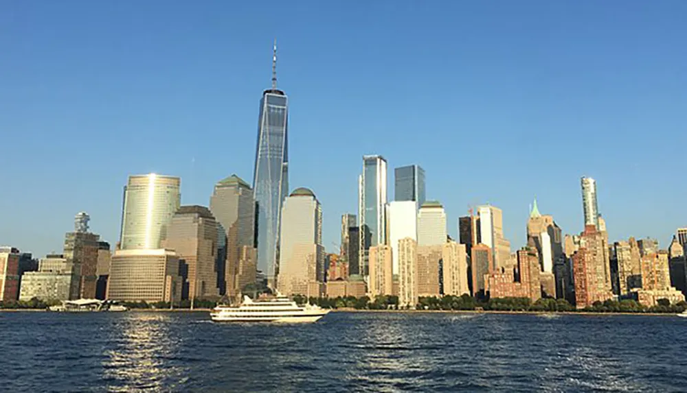 The image captures a sunny skyline view of Lower Manhattan with the One World Trade Center standing tall as seen from the water with a yacht in the foreground