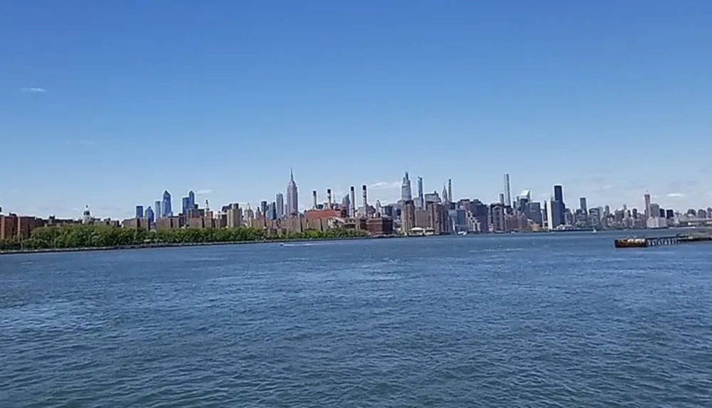 The image shows a striking view of a city skyline across a river captured on a bright and clear day