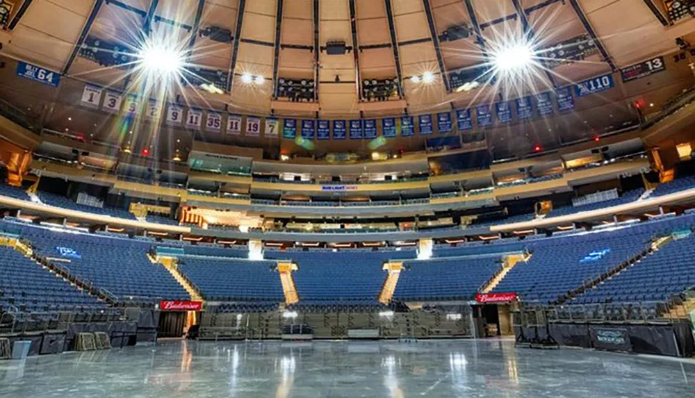 The image is of an empty indoor arena with a view of the seats and the shiny floor under bright lights ready for an event