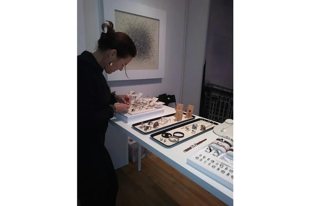 A person is examining or creating jewelry at a workbench with various pieces laid out in front of them