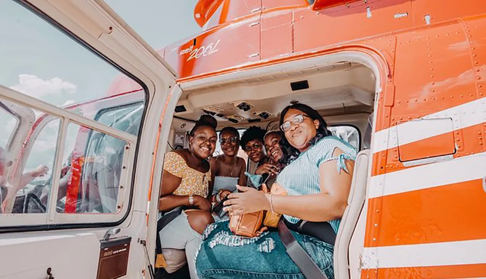 A group of happy people are posing for a photo inside a helicopter with the doors open
