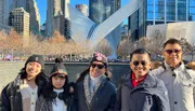 A group of five people is smiling for a photo in front of the Oculus structure in New York City on a sunny day.