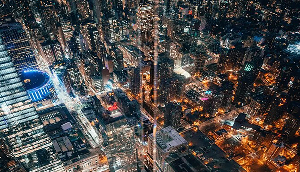 Aerial view of a densely populated city at night illuminated by countless lights and showcasing a bustling urban landscape