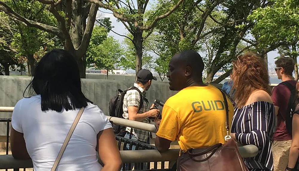 A group of people appear to be on a guided tour with a person wearing a yellow GUIDE shirt speaking to them