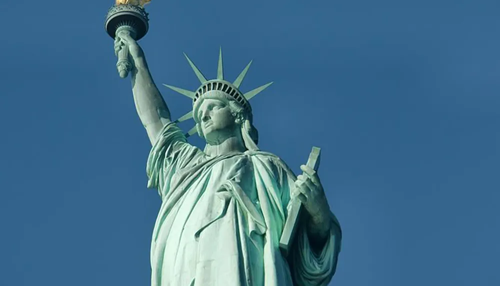 The image shows the Statue of Liberty against a clear blue sky