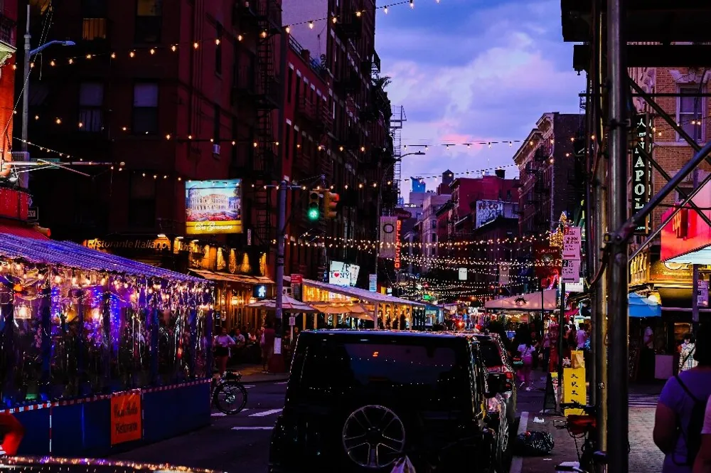 Twilight descends on a vibrant city street bustling with activity and adorned with string lights that add a festive ambiance to the lively urban scene