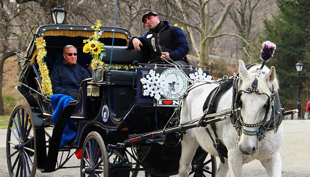 A horse-drawn carriage adorned with sunflowers and snowflake decorations carries a passenger and is guided by a coachman through an outdoor setting