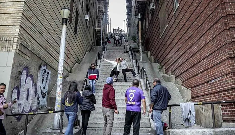People are visiting a steep urban stairway where two individuals are posing for a photo in the middle while others ascend descend or watch