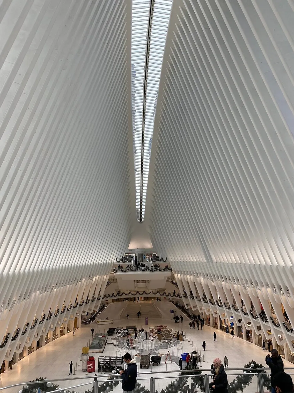 The image captures the expansive white-ribbed interior of the Oculus transportation hub at the World Trade Center site in New York City bustling with people and activity