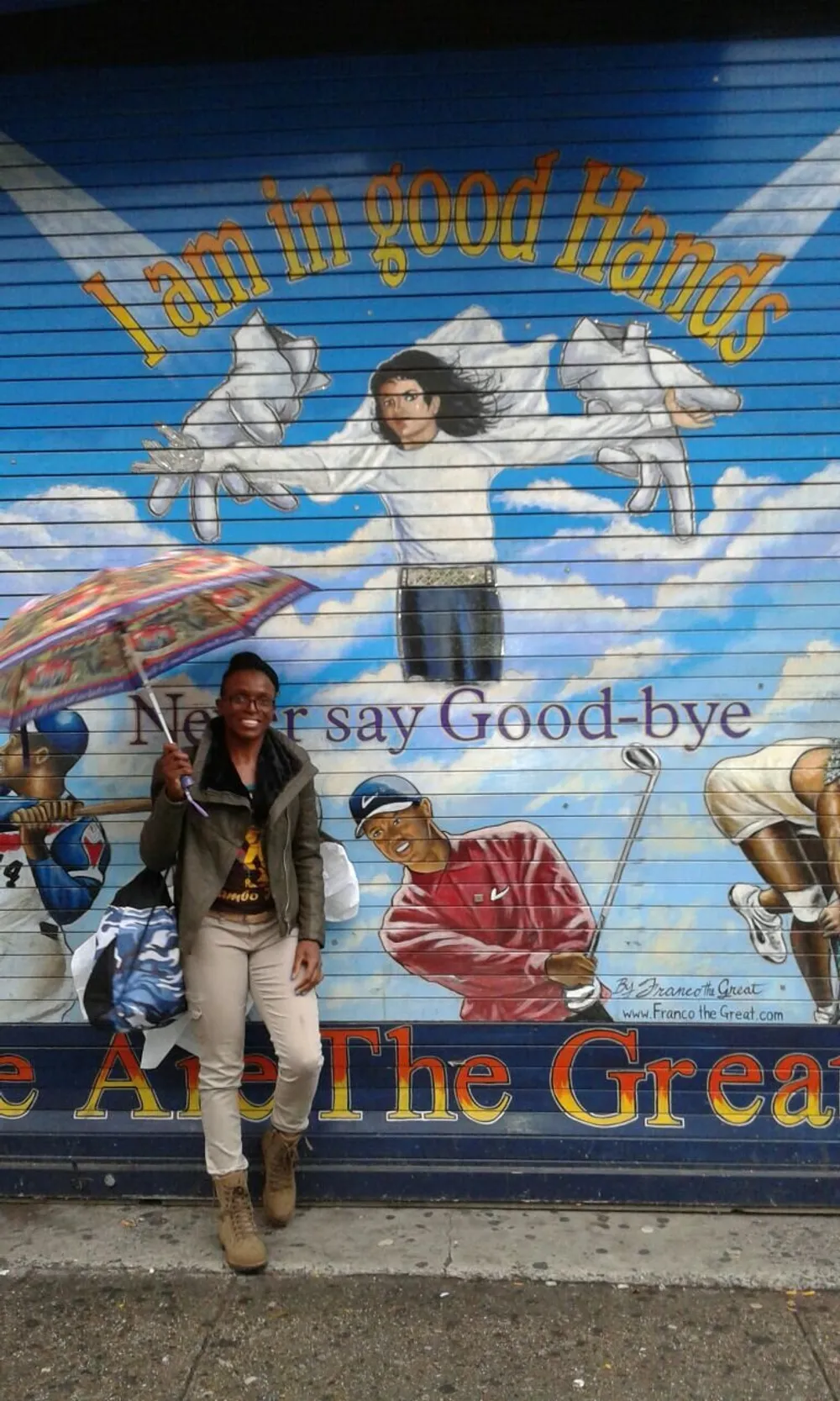 A person is standing in front of a colorful mural that states I am in good Hands and Never say Good-bye featuring various figures and the artists signature Franco the Great