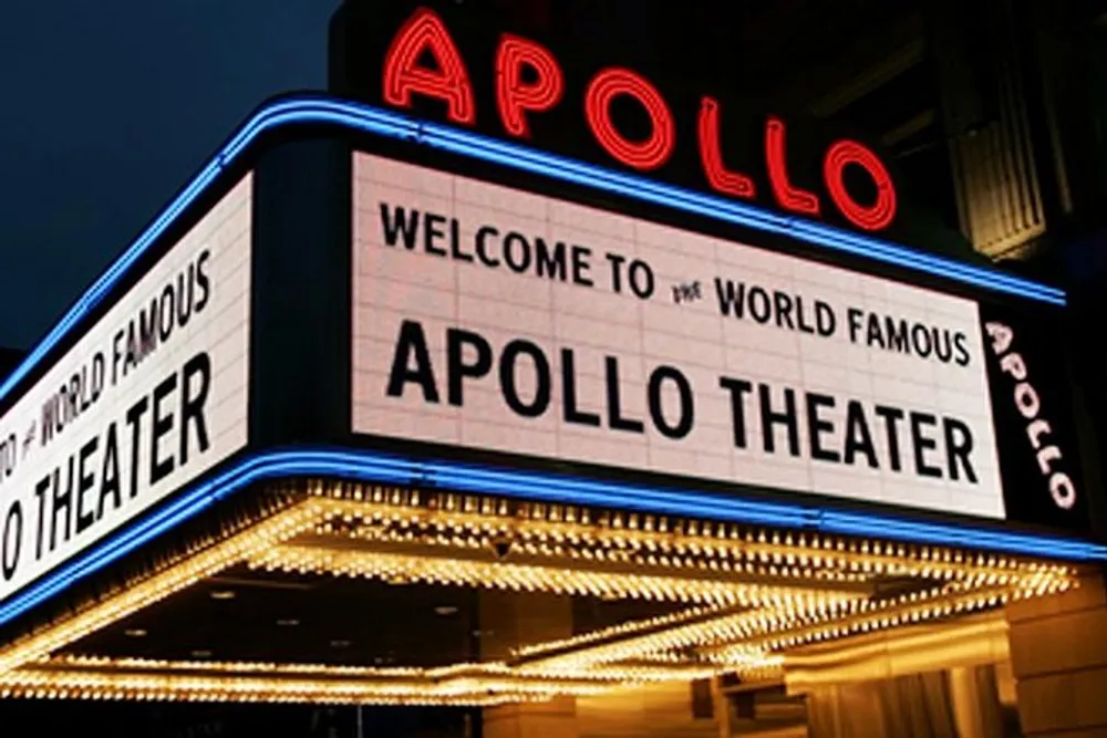 The image features the illuminated marquee sign of the world-famous Apollo Theater at night