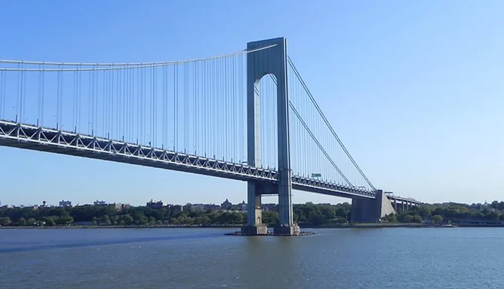 The image features a large suspension bridge with tall towers and a long span over a body of water under a clear blue sky