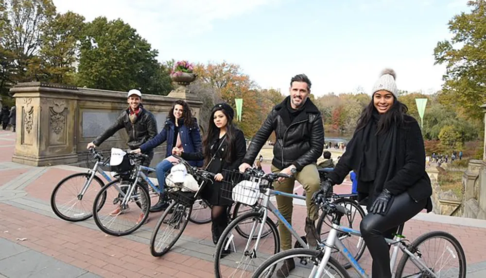 A group of five smiling people are posing for a photo while sitting on bicycles likely enjoying a day of cycling together outdoors