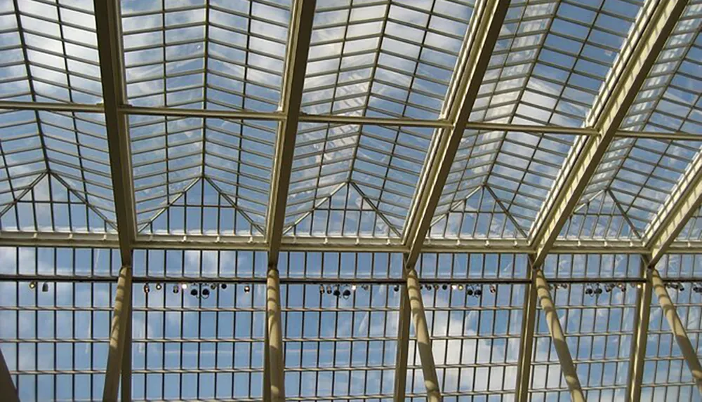 The image displays the intricate geometric pattern of a glass ceiling structure with light streaming through