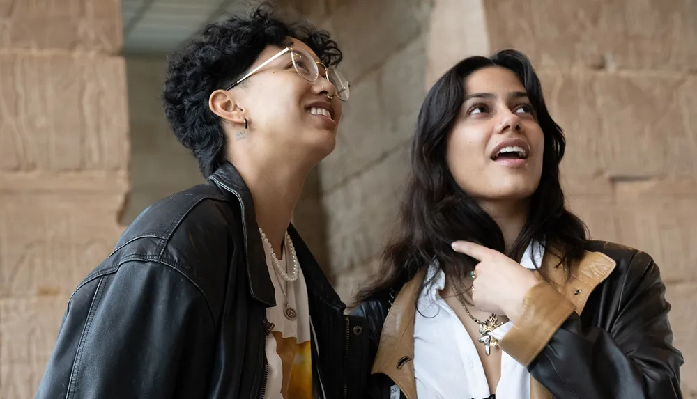 Two people are engaging in a lively conversation with one looking upwards and smiling while the other seems animated and expressive