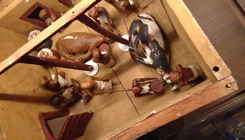 The image depicts an old worn-out foosball table with damaged and discolored figurines and playing surface suggesting heavy use or poor storage conditions