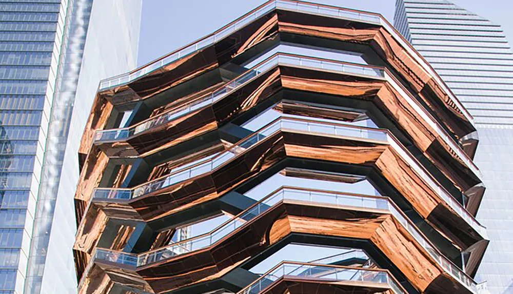 The image shows an innovative multi-tiered structure with honeycomb-like steel and glass design accentuated by copper-colored cladding set against a backdrop of modern skyscrapers