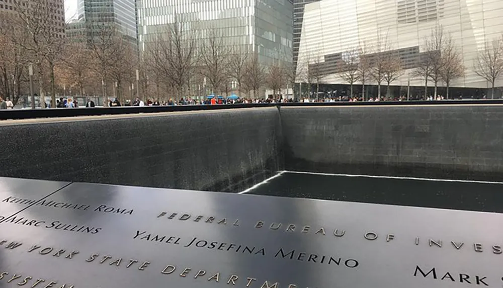The image shows the 911 Memorial in New York City with names engraved on the edge and the water reflecting the somber mood of remembrance