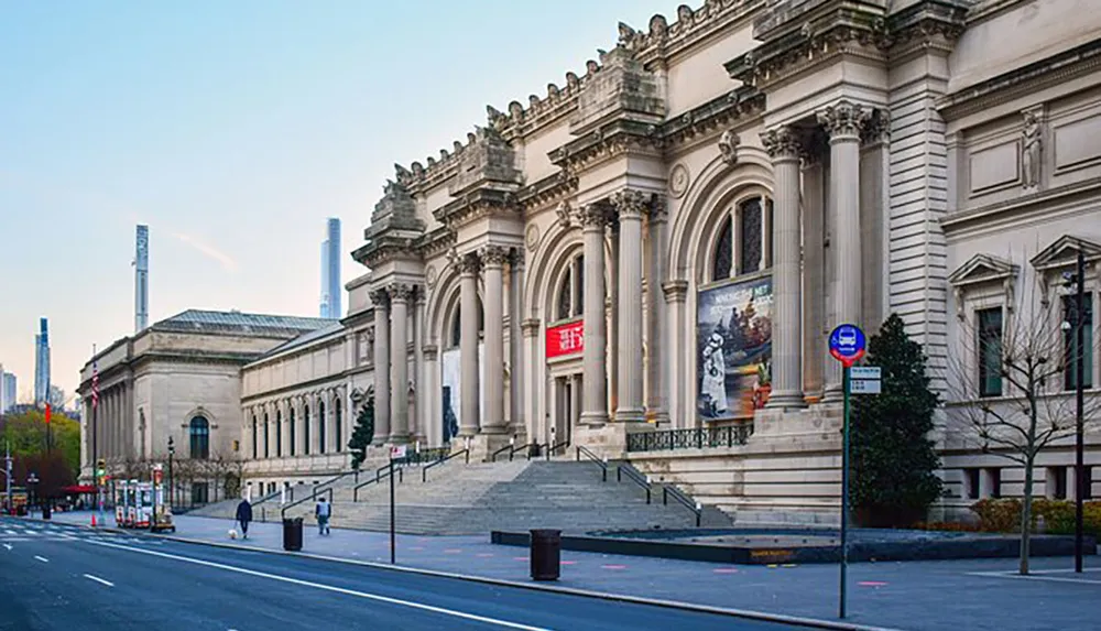 The image shows the grand exterior of a neoclassical building with steps leading up to its columned entrance likely a museum or cultural institution