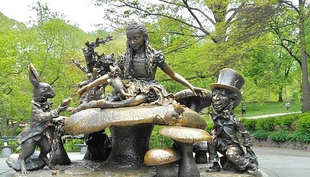 The image shows a bronze statue of characters from the Alice in Wonderland story with Alice seated at a mushroom table accompanied by the Mad Hatter and the White Rabbit set in a lush park