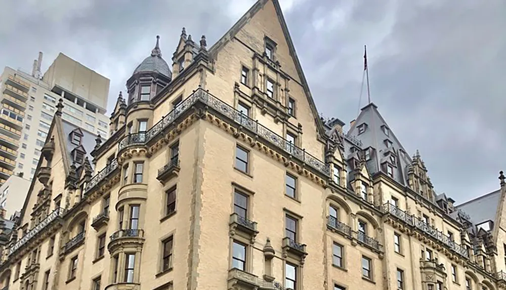The image shows a historic building with detailed stone facade work and turreted roofs contrasting with the modern high-rise structures in the background
