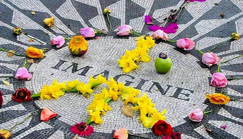 The image shows a mosaic with the word IMAGINE decorated with colorful flowers and a green apple placed on top
