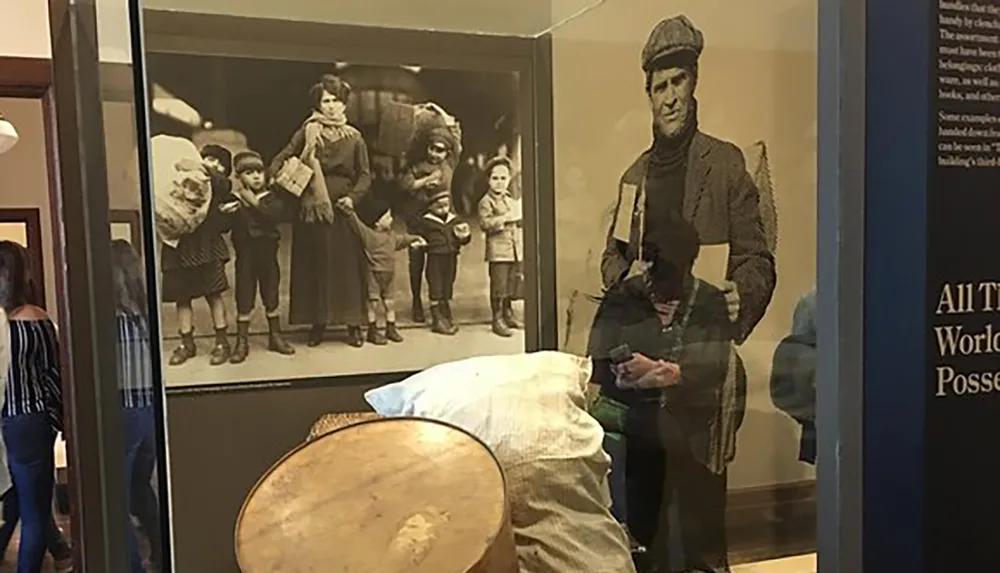 The image shows a person looking at a smartphone in a museum with a reflection creating the illusion that they are part of an old photograph of immigrants on display